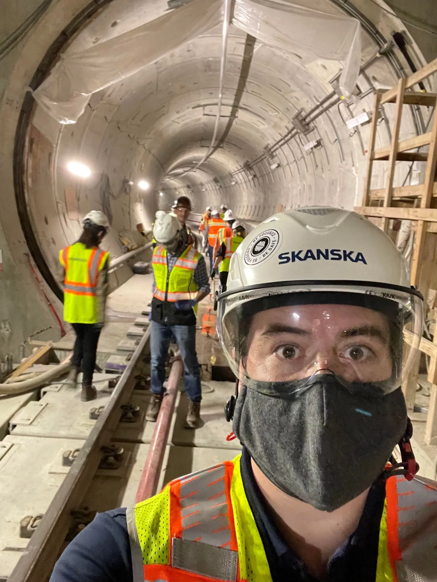 Chris in a Skanska hard hat touring a transit tunnel under construction